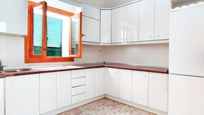 A kitchen with white cabinets, a window with wooden frames, and a tiled floor. - Belvilla by OYO Villa Cepillo I (Nijar)