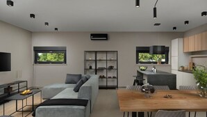 Una sala moderna con un sofá gris, una mesa de comedor de madera y una zona de cocina con ventanal.