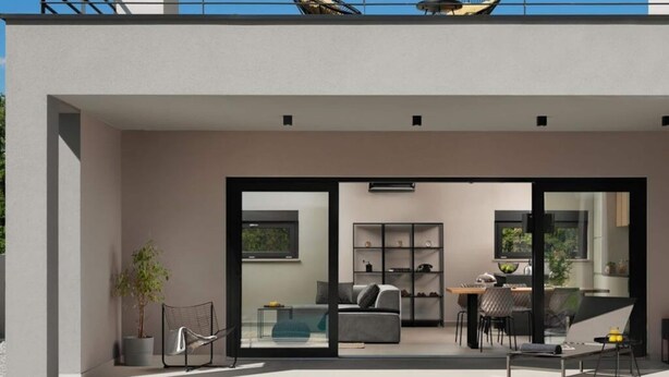 Un espacio exterior moderno con sofá, mesa de comedor y sillas, una planta en maceta y una puerta de vidrio que da a un interior con un sofá, estanterías y zona de comedor.