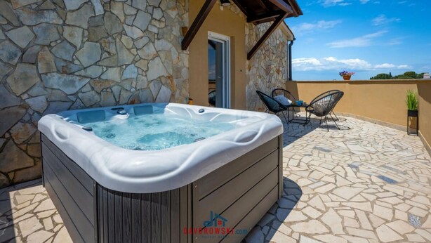 A stone wall, a hot tub, and a patio with chairs. - Boky Comfortable Holiday Residence (Vodnjan)