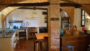 A rustic kitchen with exposed brick arches, a wooden dining table, and a built-in oven. - Nice Apartment in Trassenheide (Bonvicino)