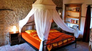 A bedroom with a four-poster canopy bed, stone walls, a wooden ceiling, and a bookshelf. - Nice Apartment in Trassenheide (Bonvicino)