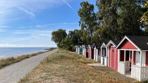 A row of beach huts with a gravel path leading to the beach. - 4 Star Holiday Home in Tomelilla (Tomelilla)