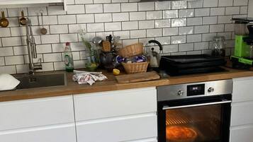 Cozinha com painel de azulejos brancos, eletrodomésticos de aço inoxidável e forno embutido.