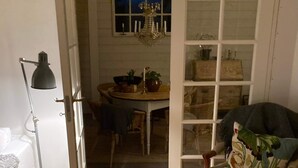 An open door leading to a dining area with a chandelier, a table with chairs, and a chair with a floral cushion. - 4 Star Holiday Home in Tomelilla (Tomelilla)