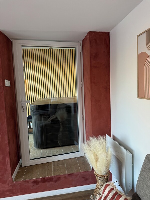 A room with a sliding glass door leading to a balcony, a radiator, and a decorative plant. - Maison Rénovée Avec un Jacuzzi Privatif. A 7 Minutes à Pieds du Centre-ville (Dinan)