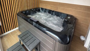 Un jacuzzi con un revestimiento de pared de madera y una pequeña zona de estar.