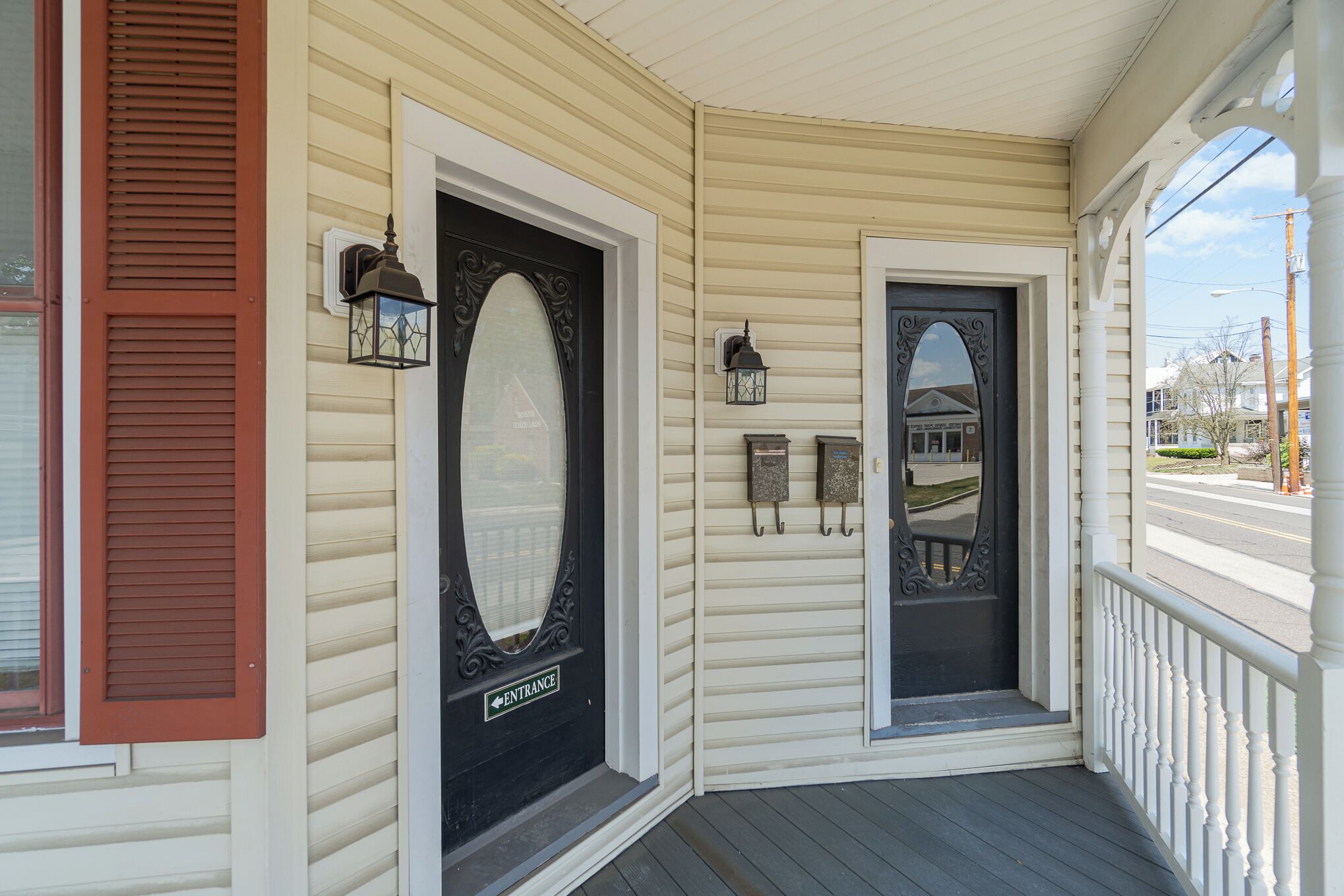 A porch with a black door marked "ENTRANCE" and a small mailbox.