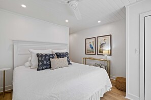 A bedroom with a large bed, white walls, a ceiling fan, and two framed pictures on the wall. - 1590 Lagoon Villas at The Sea Pines Resort (Hilton Head Island)