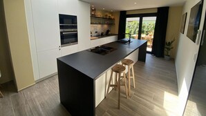 Eine moderne Küche mit Kochinsel, integrierten Geräten und einem Oberlicht.