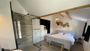 Ein modernes Schlafzimmer mit einem großen Bett, einer Duschkabine aus Glas und einem weißen Waschbecken.