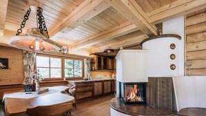 A cozy cabin interior with a central fireplace, wooden walls, and a dining area with a table and chairs.