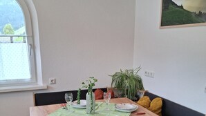 A dining area with a wooden table, bench seating, a window, and a painting on the wall. - Apartment in Tyrol Near Ski Slopes (Fliess)