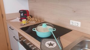 A kitchen with a modern stove, a coffee maker, a pot on the induction cooktop, and a wooden sign that says "Relax". - Apartment in Tyrol Near Ski Slopes (Fliess)