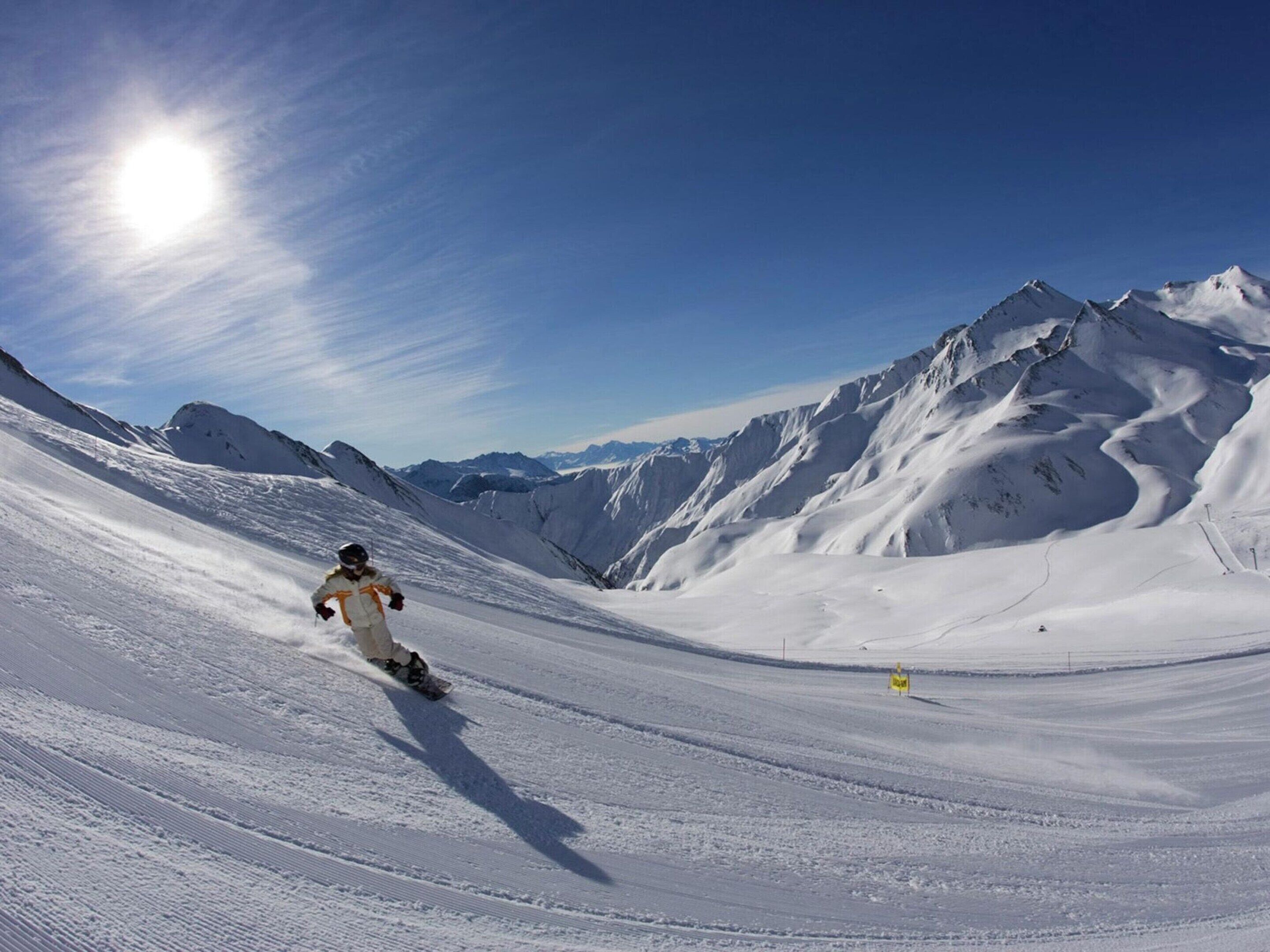 A snowboarder on a snowy slope with mountains in the background.
