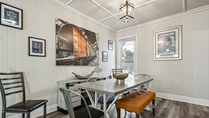 Un coin repas avec une table en bois, des chaises en métal et un grand tableau accroché au mur.