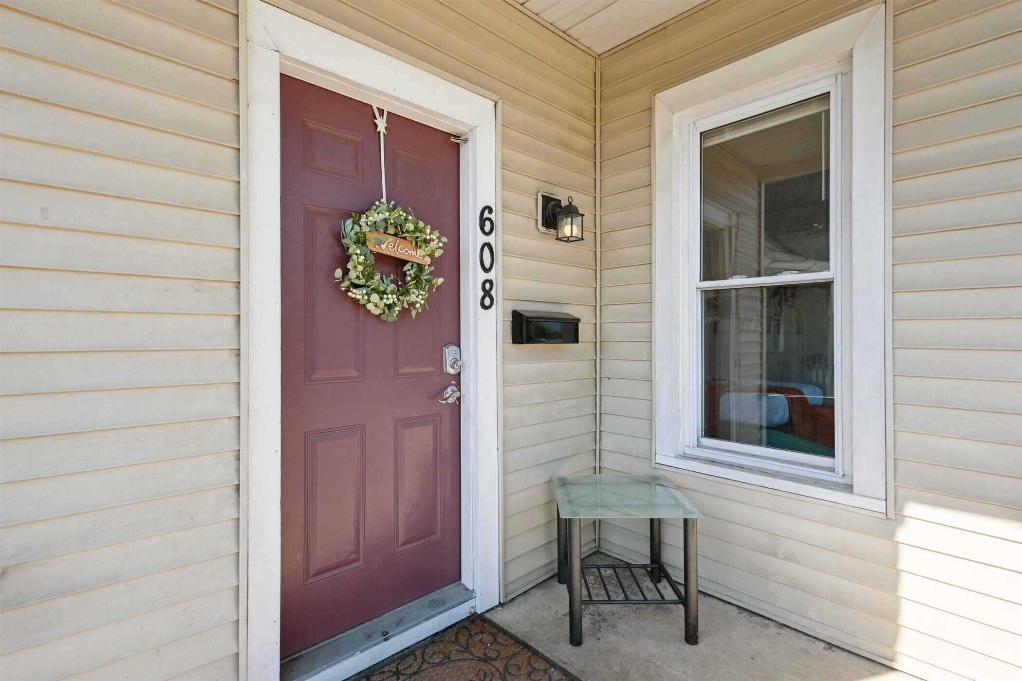 A house with a red door, a welcome wreath, and a mailbox.