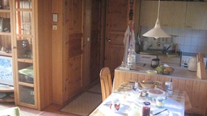 A wooden interior with a dining table set for four, kitchen cabinets, and a hanging light fixture. - Holiday Home Monkfish House (Warin)