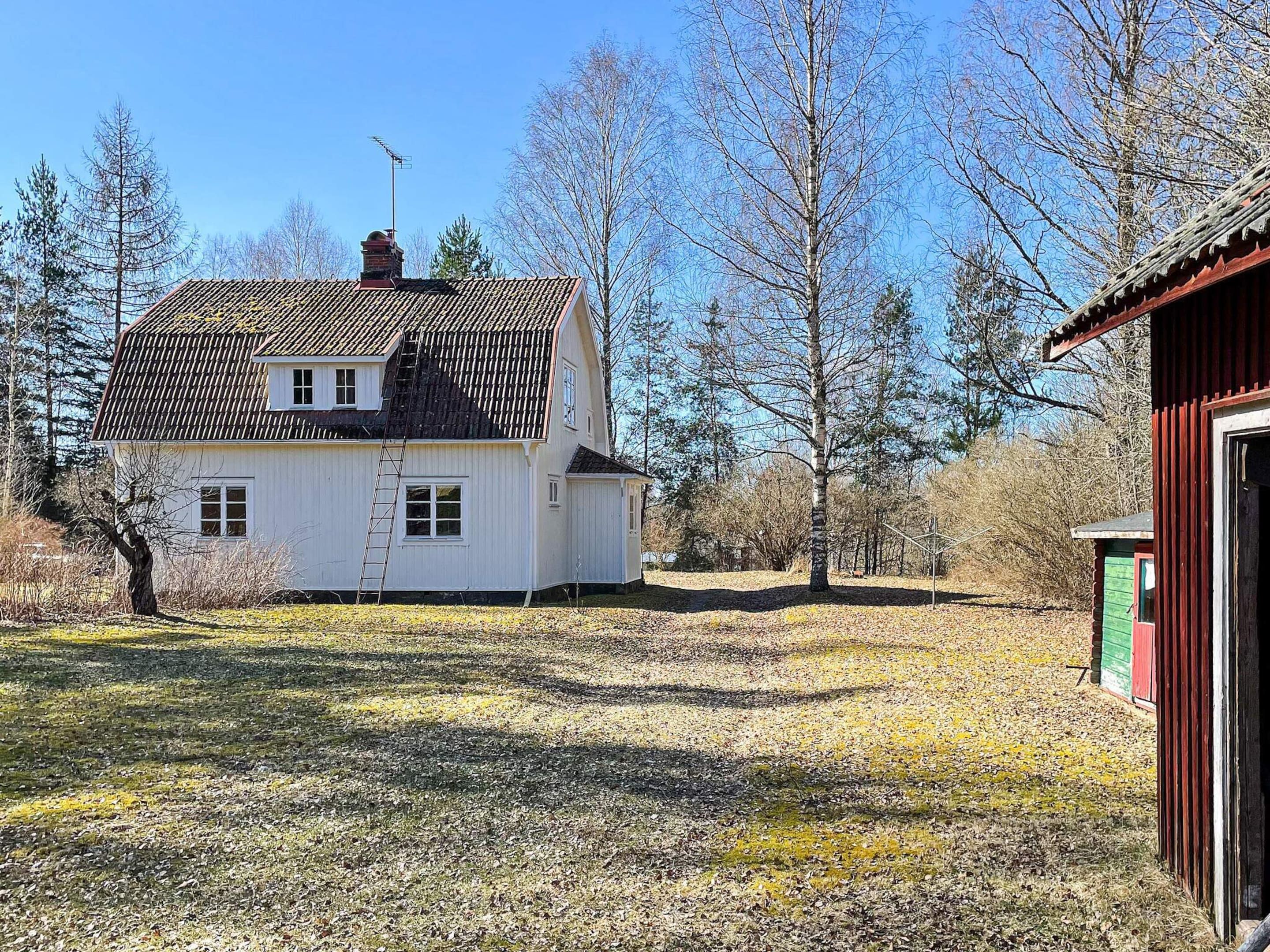 A white house with a tiled roof, a chimney, and a small attached shed.