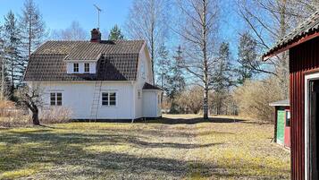 A white house with a tiled roof, a chimney, and a small attached shed.
