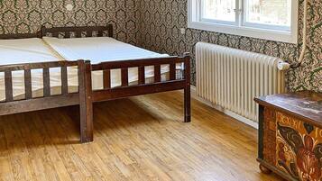Una habitación con una cama de madera, un radiador y una ventana.