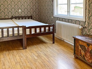 A room with a wooden bed, a radiator, and a window. - 4 Person Holiday Home in Hoje (Höje)