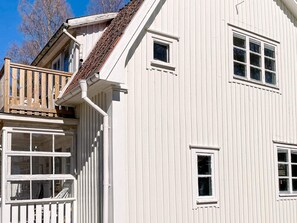 A white building with a wooden deck and multiple windows.