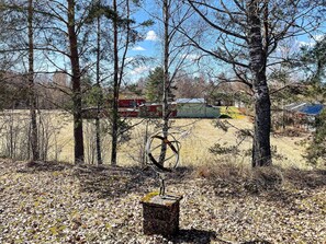A forested area with a bicycle leaning against a tree, a fire truck in the background, and a building with a red roof. - 4 Person Holiday Home in Hoje (Höje)