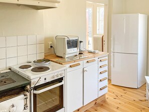 A compact kitchen with a stove, oven, microwave, and a refrigerator. - 4 Person Holiday Home in Hoje (Höje)