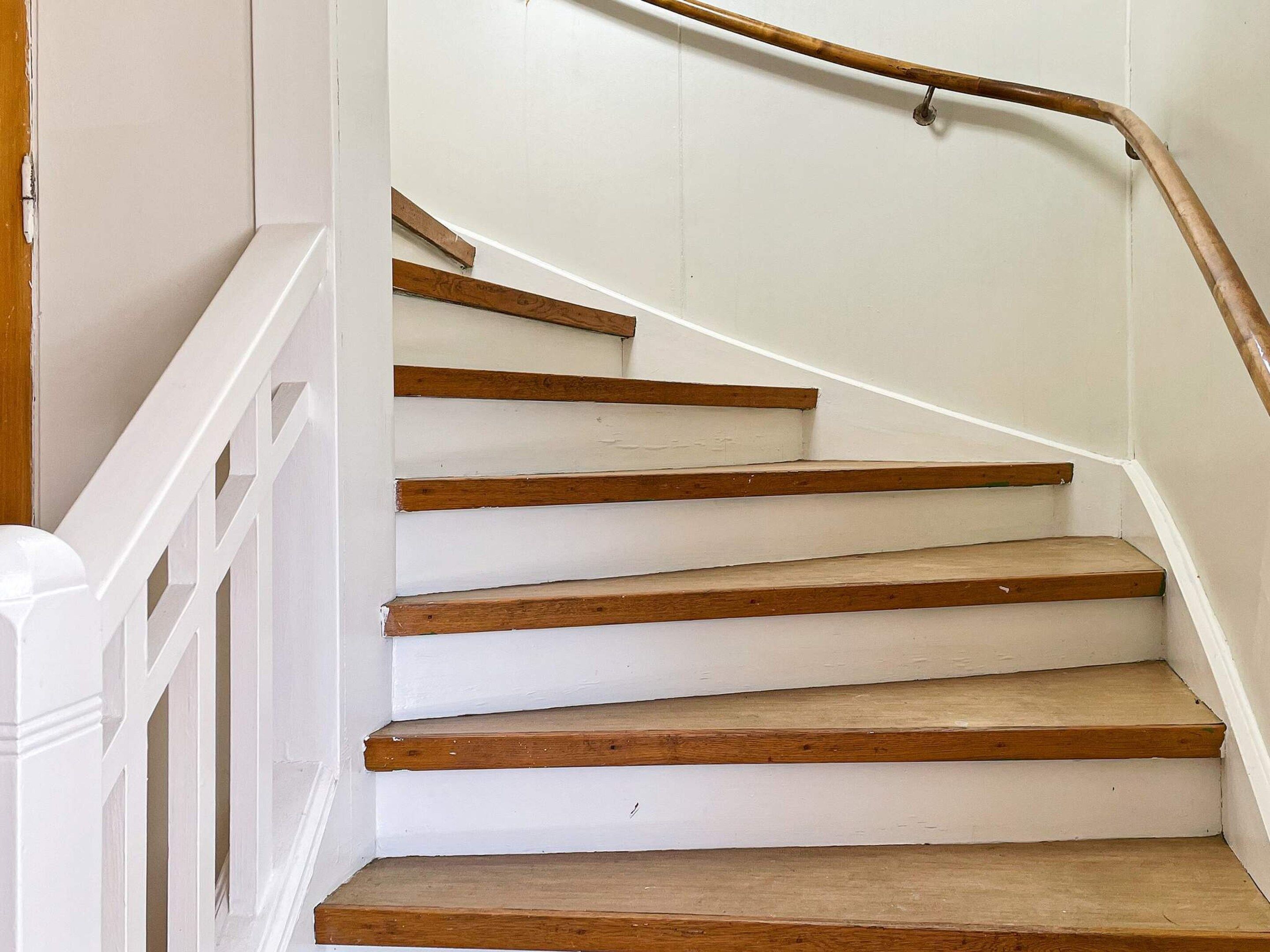 A staircase with white walls and wooden steps.