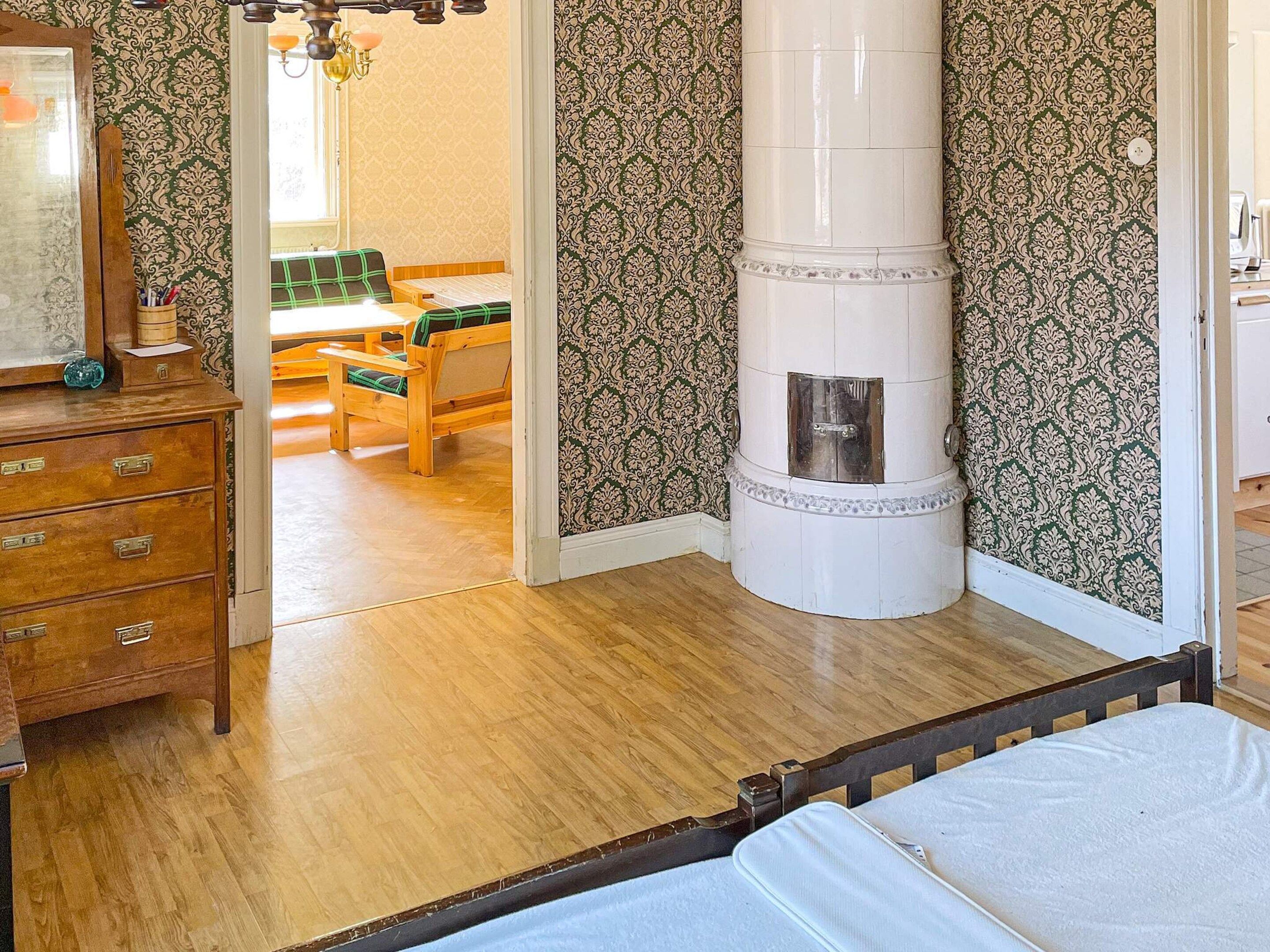 A room with a bed, wooden dresser, and a fireplace.