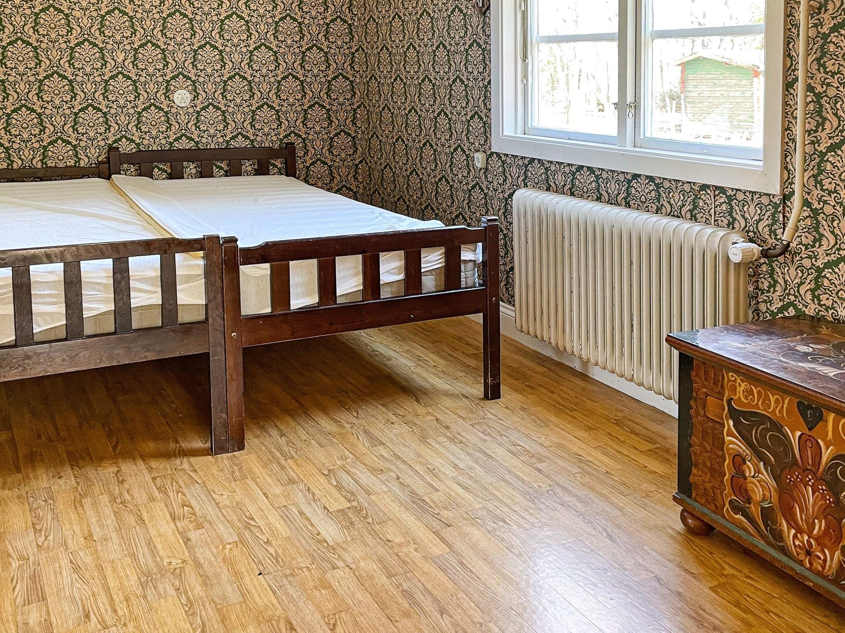 Ein Zimmer mit einem hölzernen Bett, einem Heizkörper und einem Fenster mit Außenblick.
