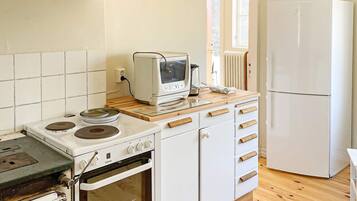 Cozinha compacta com fogão, forno, torradeira e geladeira.