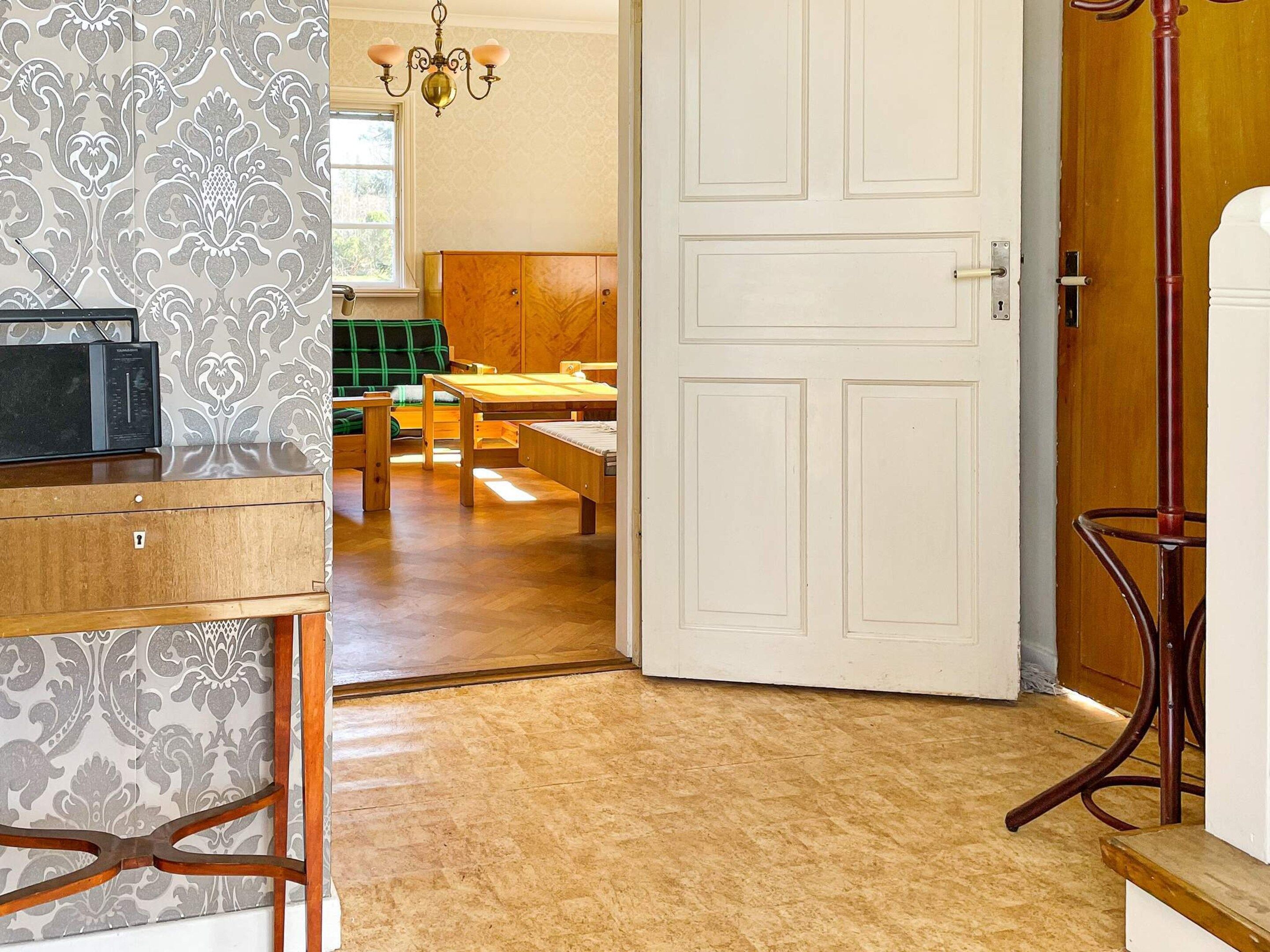 A room with a wooden table, a bench, and a white door.