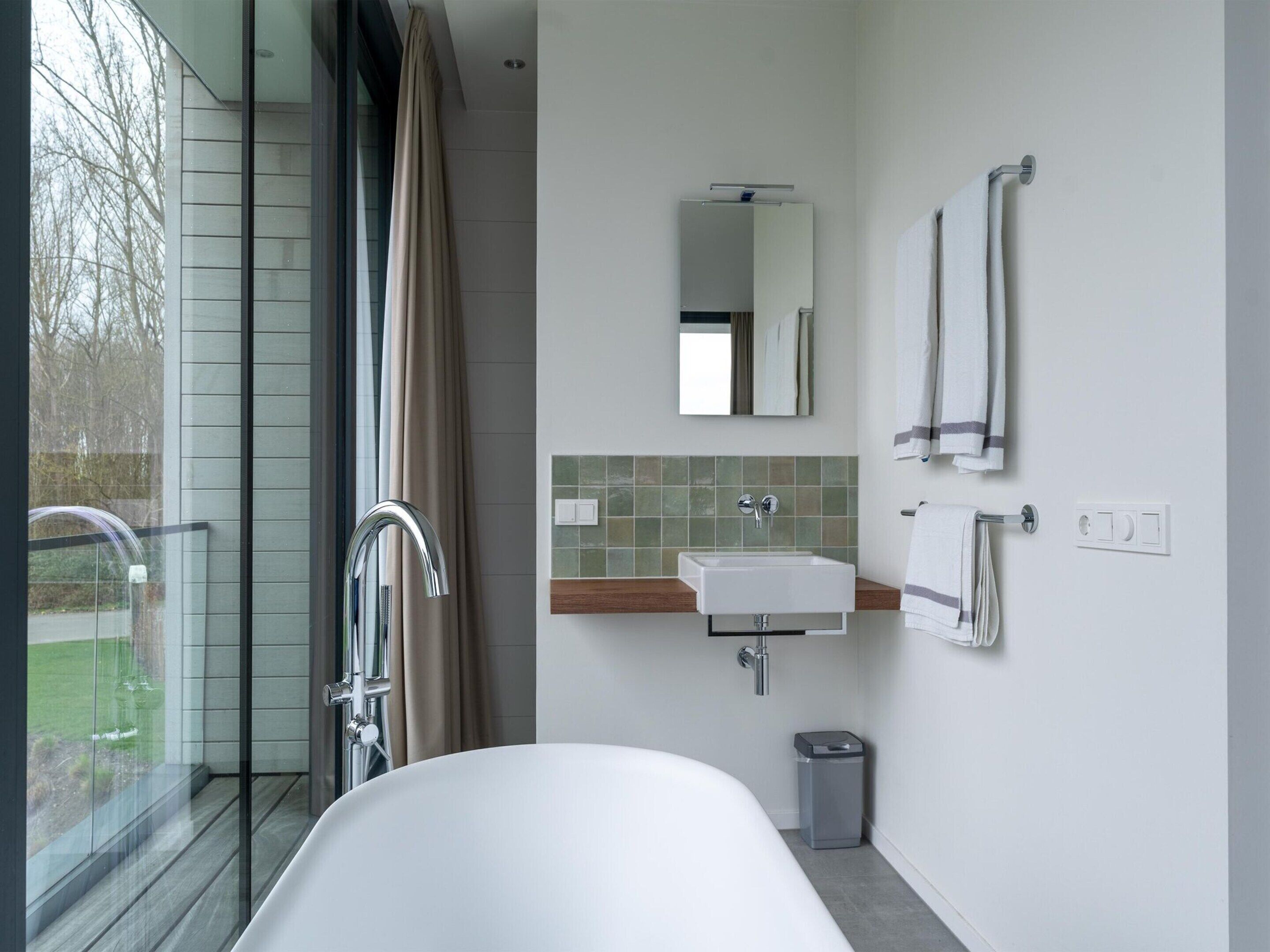 A modern bathroom with a bathtub, a sink, a mirror, and a shower.