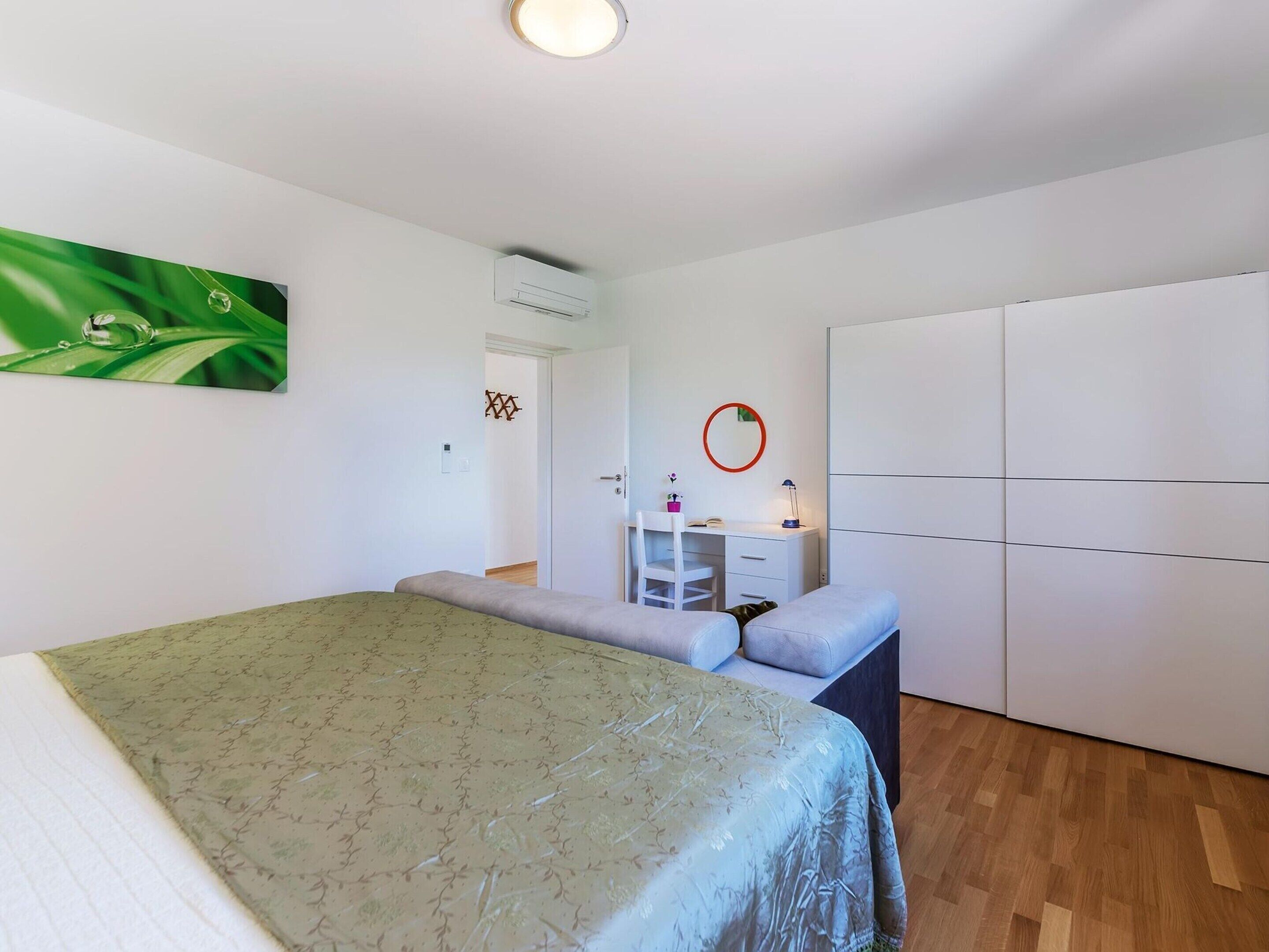 Une chambre comprenant un lit, un bureau, une armoire et un appareil de climatisation.