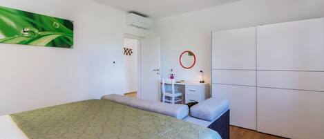 Une chambre comprenant un lit, un bureau, une armoire et un appareil de climatisation.