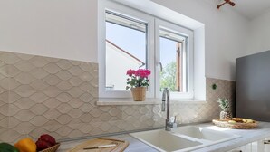 A kitchen with a double sink, a wooden cutting board, and a fruit basket. - Large Holiday Home With Swimming Pool (Labin)