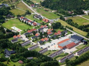 Eine Vogelperspektive auf ein Wohngebiet mit mehreren Häusern, einem großen Gebäude mit rotem Dach und einem Spielplatz.