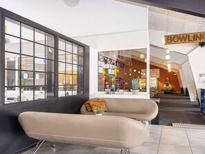 Ein modernes Interieur mit einer Couch, einem großen Fenster und einem Schild mit der Aufschrift 'BOWLING'.