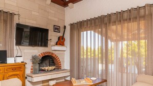Ein gemütliches Wohnzimmer mit Kamin, Fernseher und Gitarre.