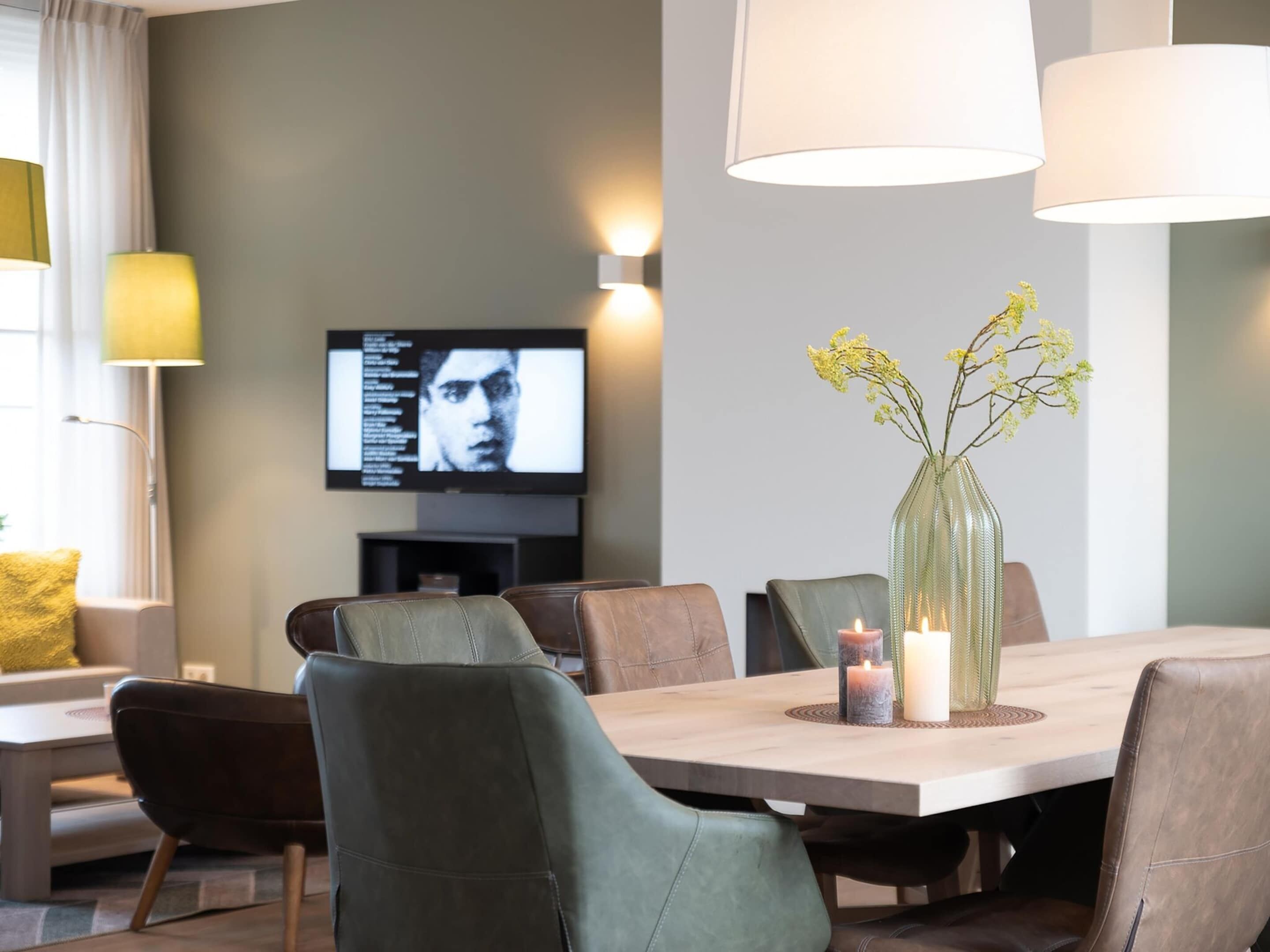 A modern dining area with a wooden table, leather chairs, and a vase with flowers.