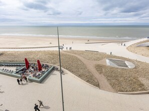 Un paseo marítimo con un café, zonas de estar y una plataforma de observación con vistas al mar.