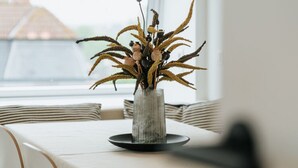 Une table ornée d’un vase contenant des plantes séchées, dans un décor moderne.