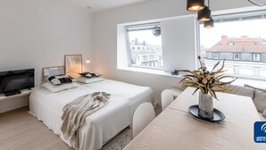 Une chambre moderne avec un lit, une table de chevet, une télévision et une fenêtre donnant sur la ville.