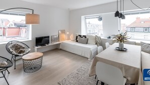 Un appartement moderne comprenant un espace de vie, un coin repas et une grande fenêtre donnant sur la ville.