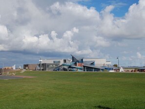 A modern building with a unique architectural design, featuring a prominent sloped roof and a large glass facade. - Holiday Home Kleiner Friese Dangast (Varel)