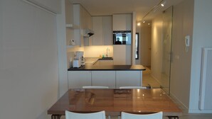 A modern kitchen with a central island, white cabinets, and a wooden dining table with two chairs.