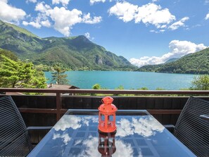Une table avec un plateau en verre et une lanterne rouge, donnant sur un lac avec des montagnes en arrière-plan.