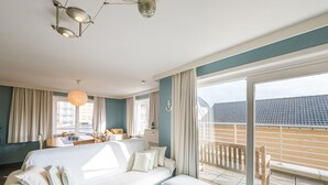 Une chambre d’hôtel moderne dotée d’un grand lit, d’un coin salon et d’un balcon offrant une vue sur la ville.